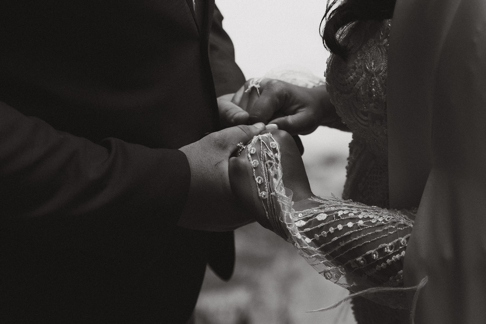 Close up of couple holding hands after eloping to Alaska in a beautiful forested area.