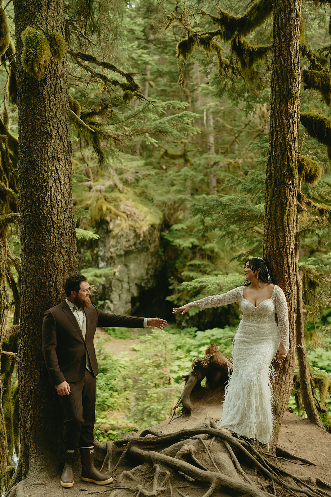 Bride and groom reaching for one another in forest during outdoor bridal portraits