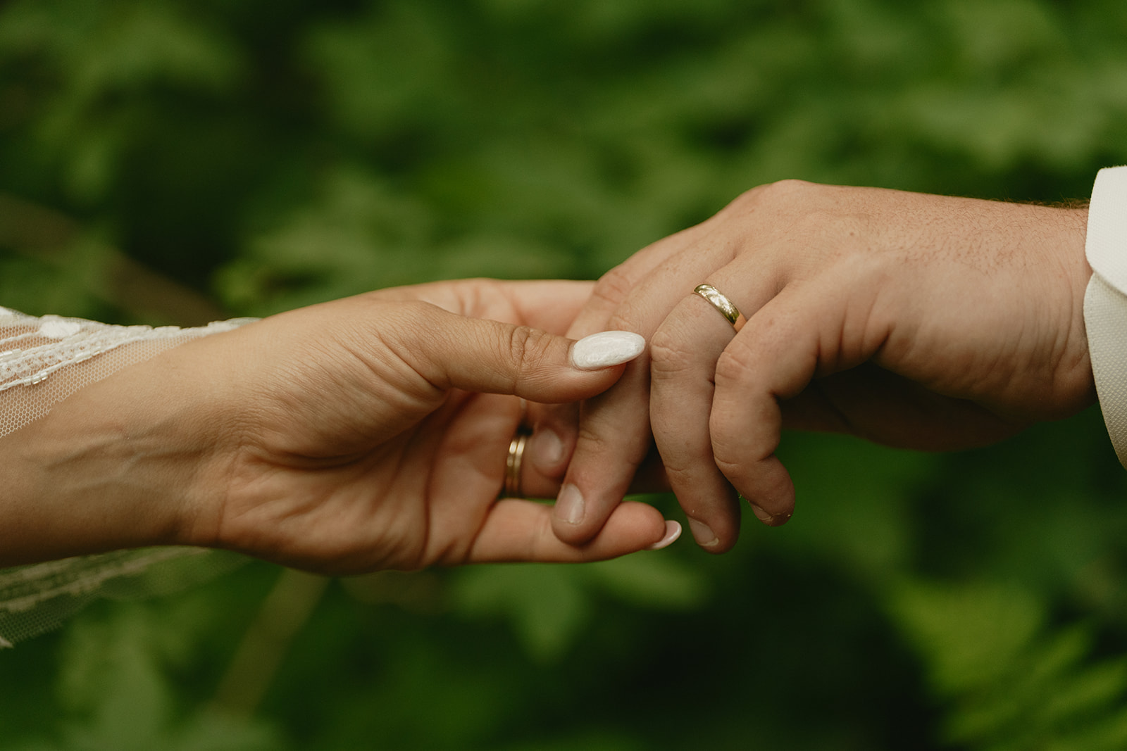 Close up of bride and groom holding hands and showing off their wedding bands