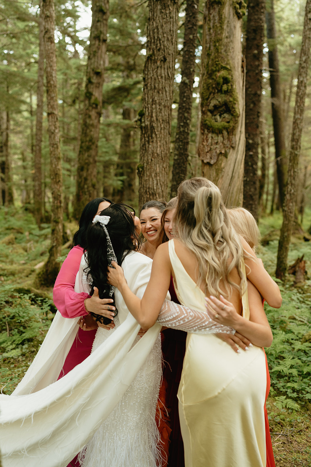 Bridesmaids all embrace after seeing bride in wedding gown getting ready to celebrate her eloping to Alaska