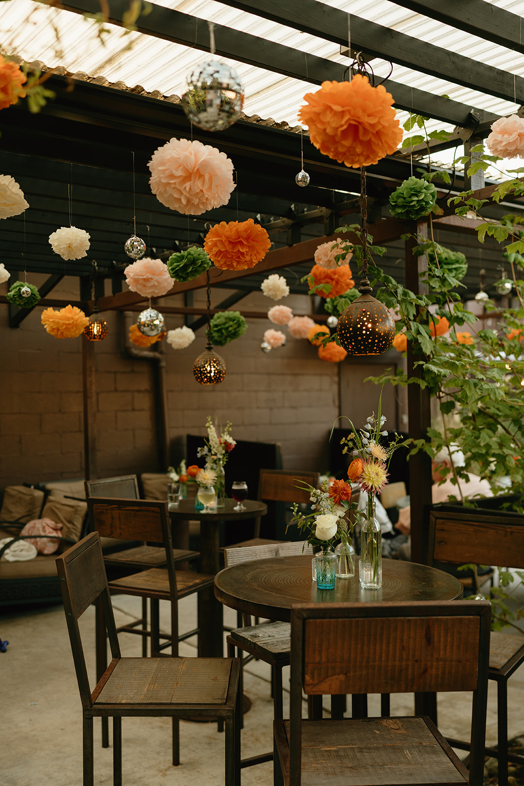 Eclectic outdoor reception space with paper lanterns, string lights, and colorful flowers creating a cozy and playful atmosphere.