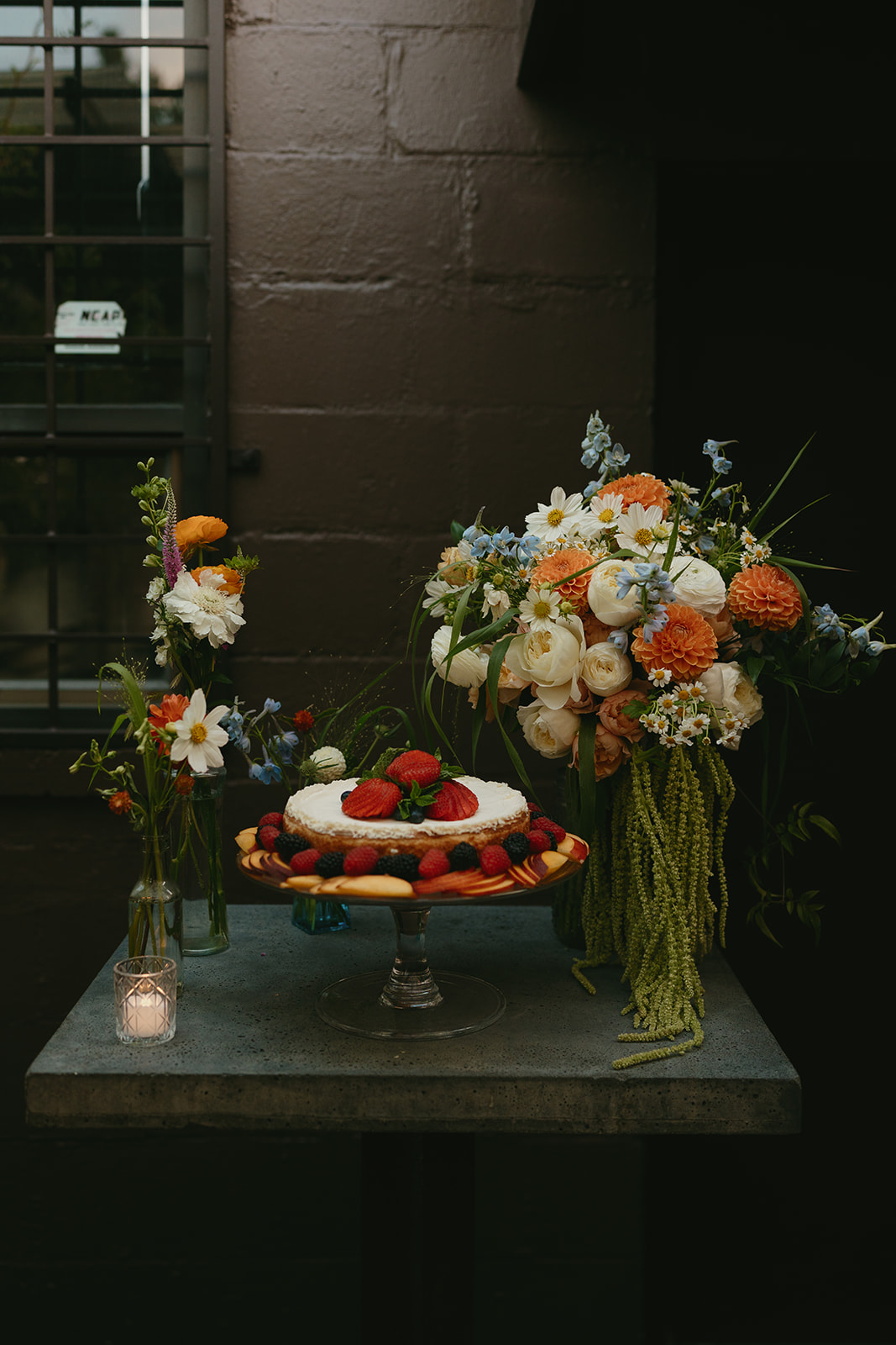 Romantic dessert and floral table setup featuring a fruit-topped tart and vibrant summer blooms at a wedding venue in Washington.