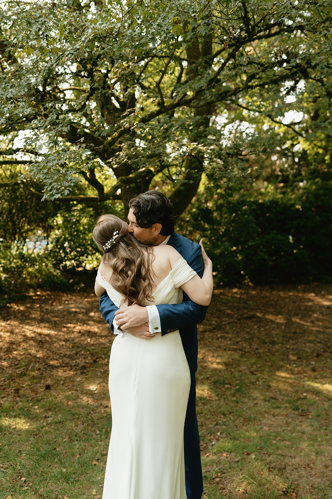 Couple holding each other under a tree in quiet embrace, soaking in the stillness after exchanging vows.