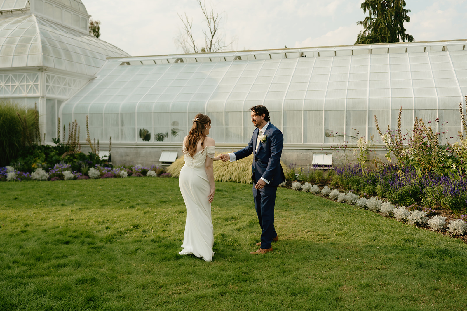 Couple dancing in front of a white conservatory, their greenhouse wedding celebration spilling into the garden lawn.