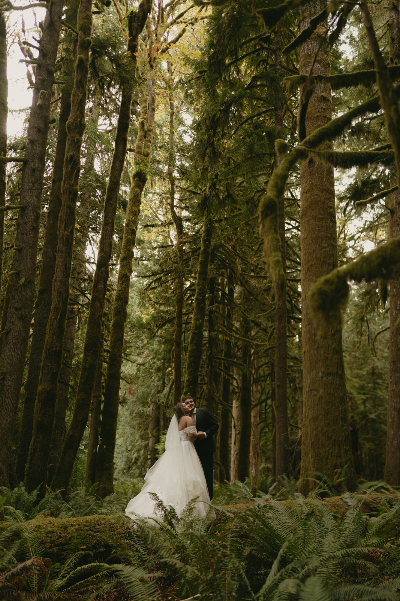 Bride and groom standing on large log in Olympic National Park, embracing and soaking in the moment of just saying their vows
