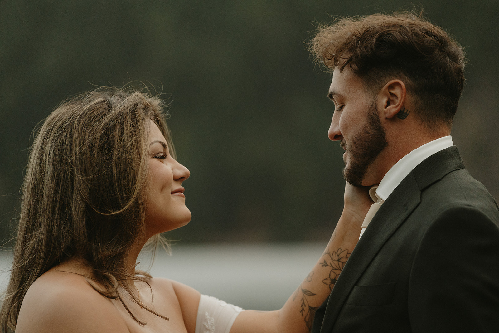 A close-up of the bride cupping the groom’s face, smiling at him softly during their Olympic National Park elopement.