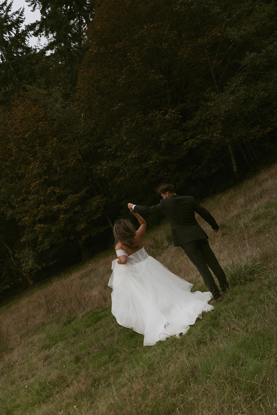 The couple dances in an open grassy meadow, the bride's dress flowing as the groom spins her during their Olympic National Park elopement.