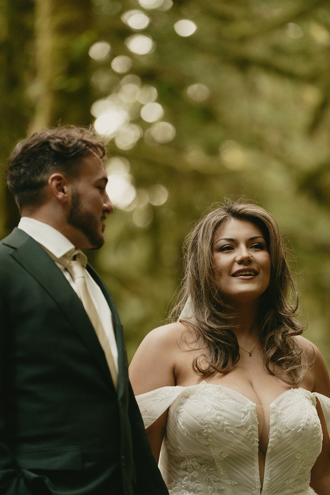 A close-up portrait of the bride and groom surrounded by soft light and greenery, sharing a peaceful moment in the forest.