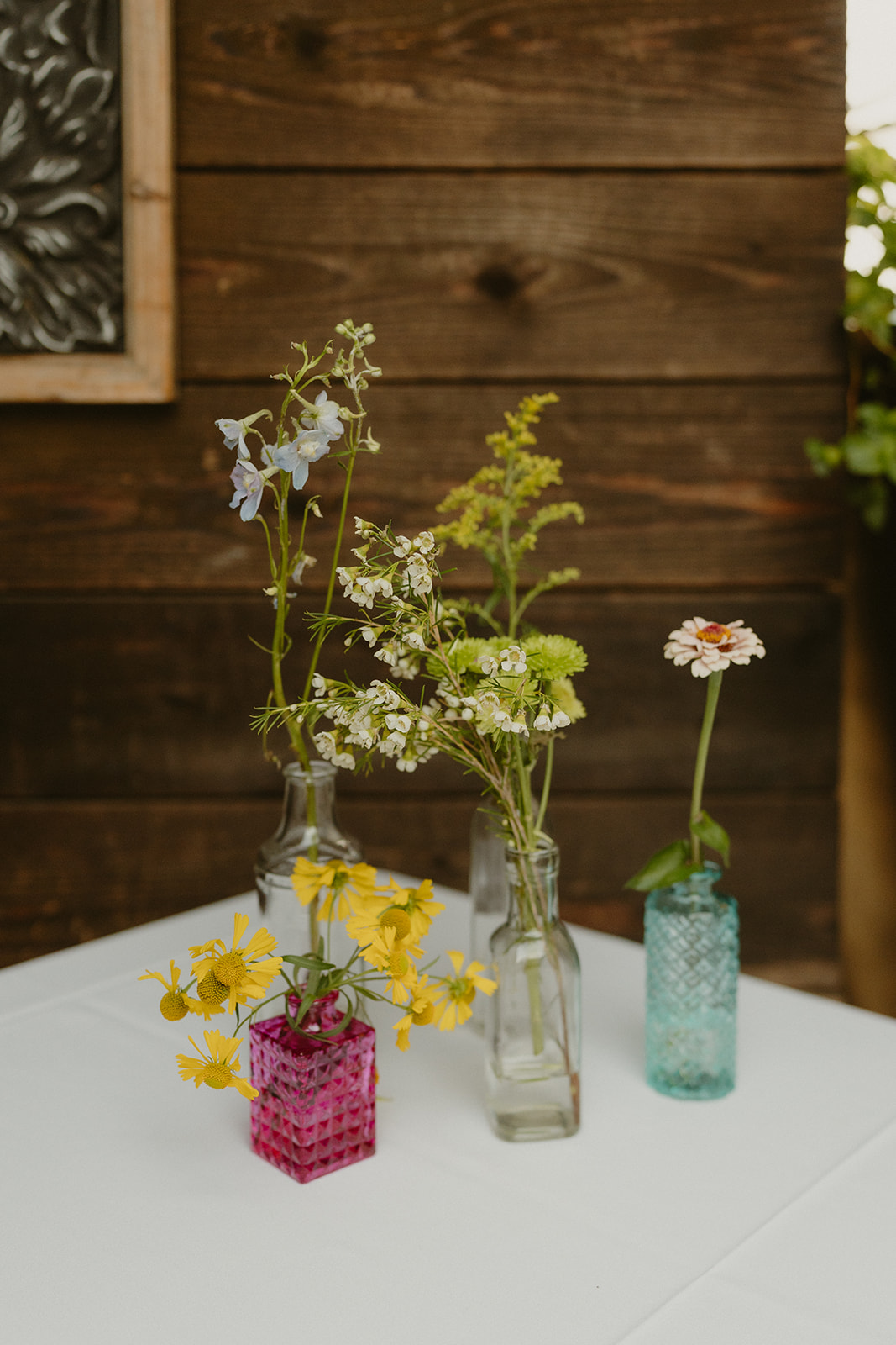 Eclectic collection of wildflowers in vintage glass vases as a simple and charming wedding table arrangement.