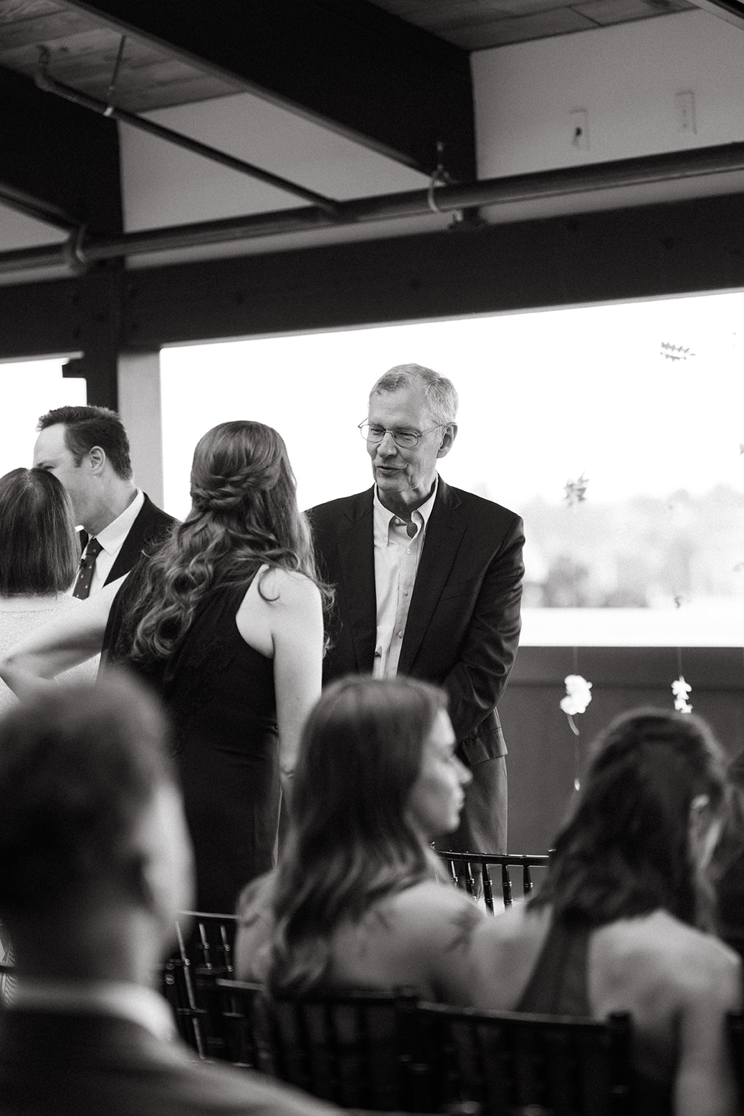 Black and white candid of guests sharing a quiet moment before the ceremony begins.