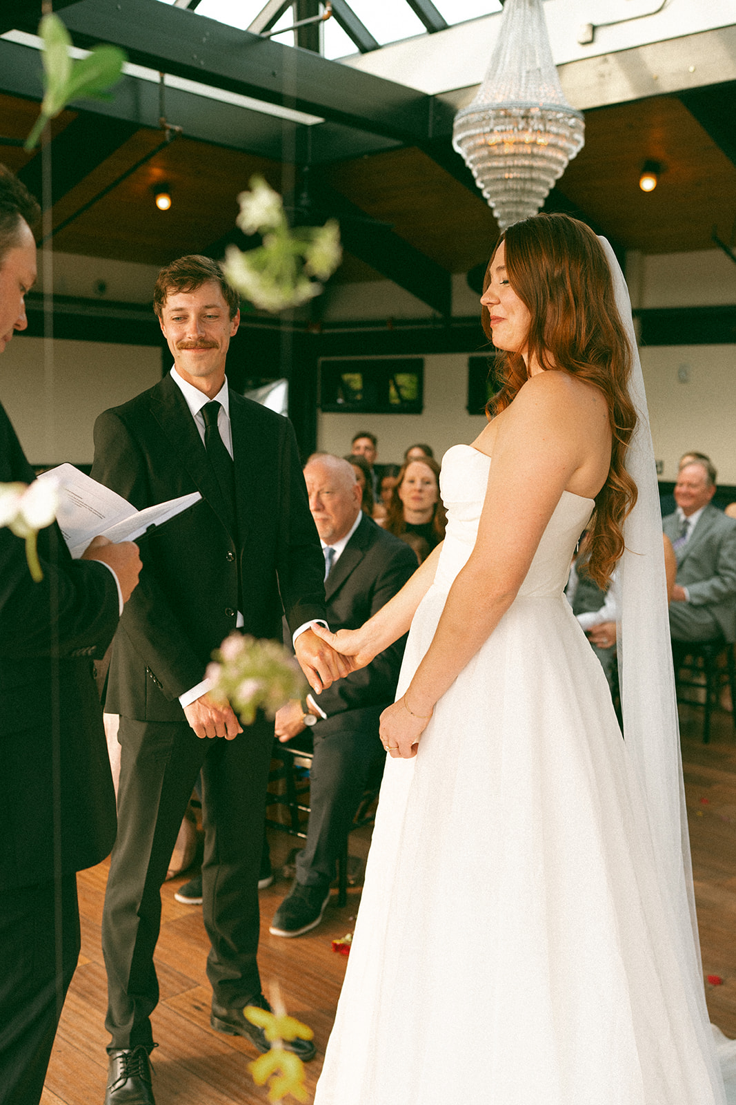 Emotional moment as the bride and groom hold hands and share a quiet smile during their vows.