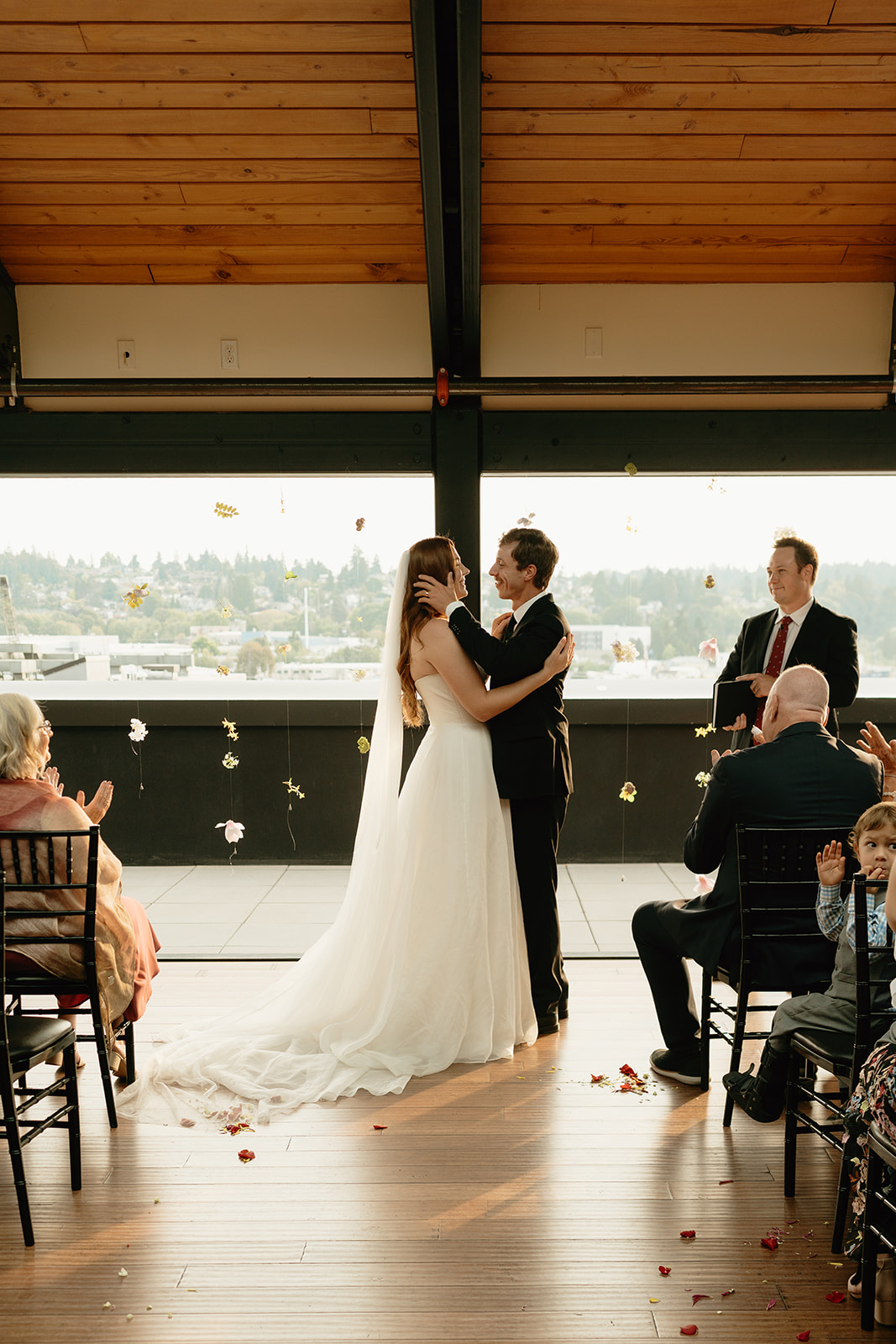 Couple shares their first kiss as newlyweds during an indoor ceremony with a view of the Washington skyline in the background.