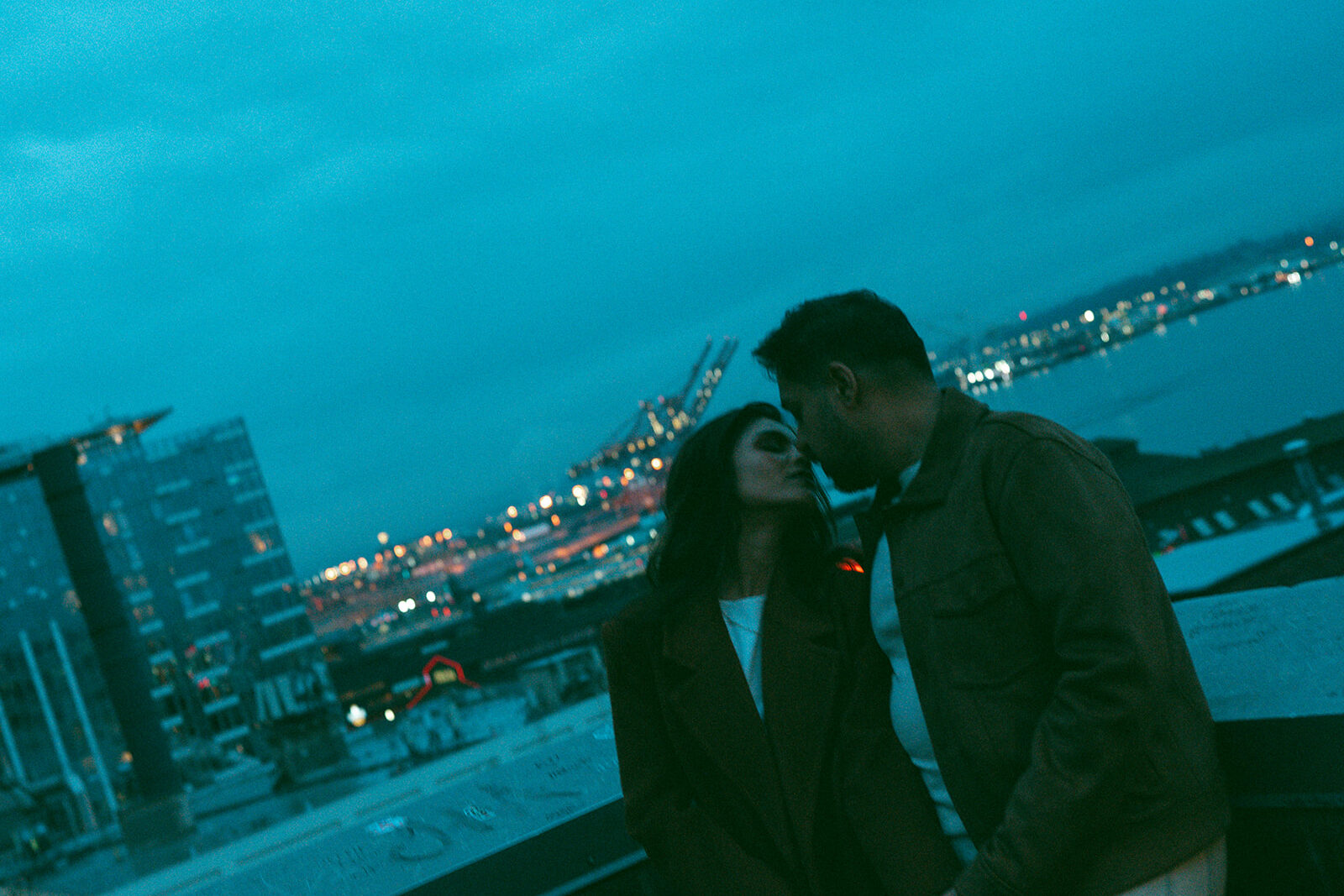A cinematic couple kissing while overlooking the Seattle Waterfront at dusk