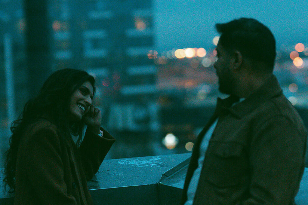 A cinematic couple sneaking a flirty glimpse at each other as they overlook the Seattle waterfront at dusk