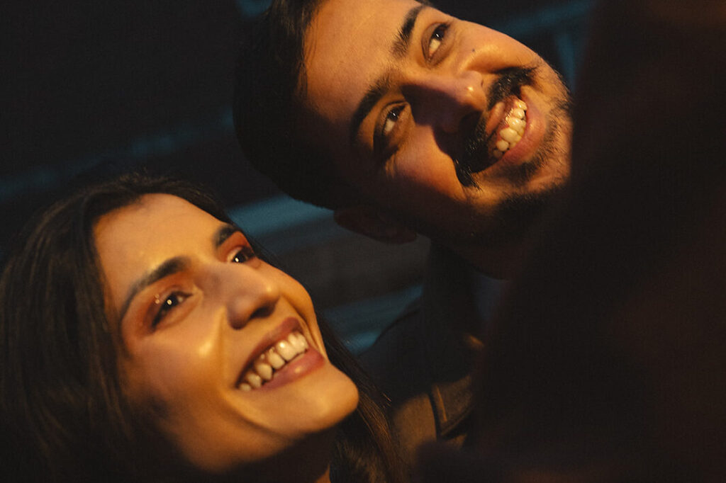 A cinematic couple having fun and smiling under a street light