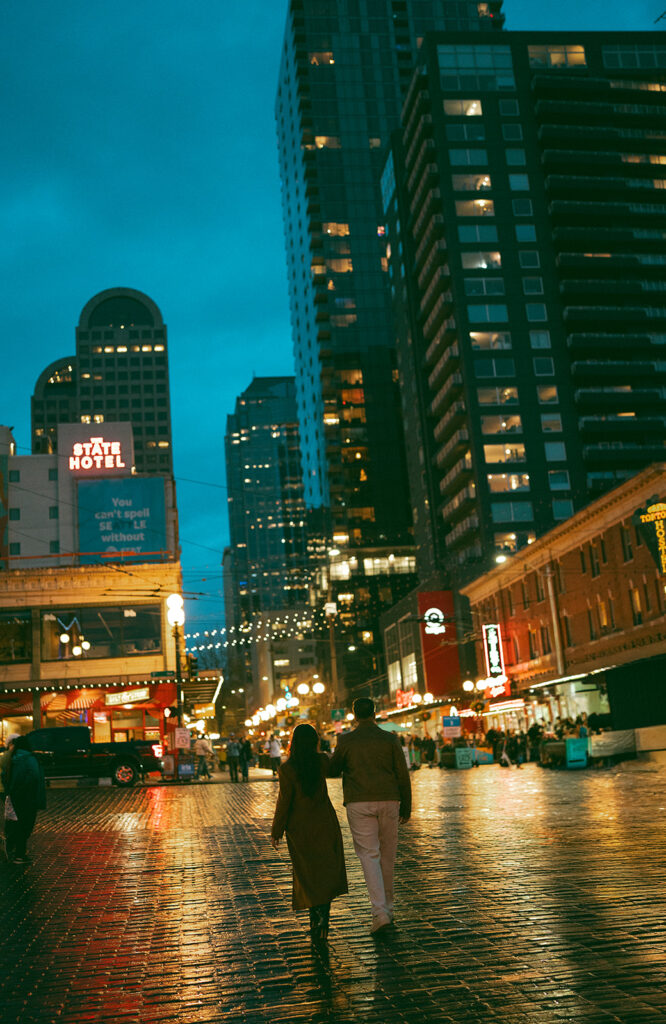 Cinematic couple running through the streets of Seattle at night time, the vibrant city lights glowing behind them