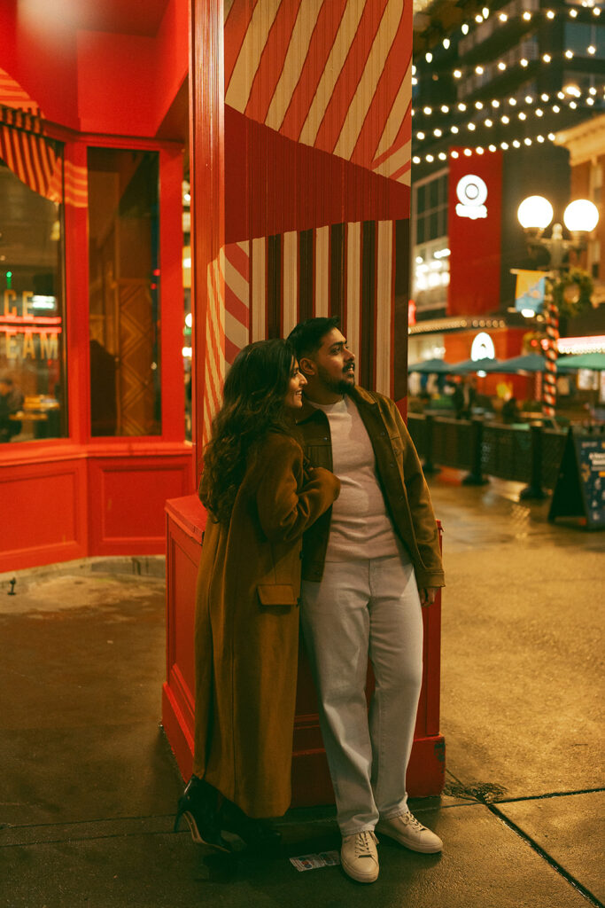 A cinematic couple cozying up in front of a bright red market in Seattle