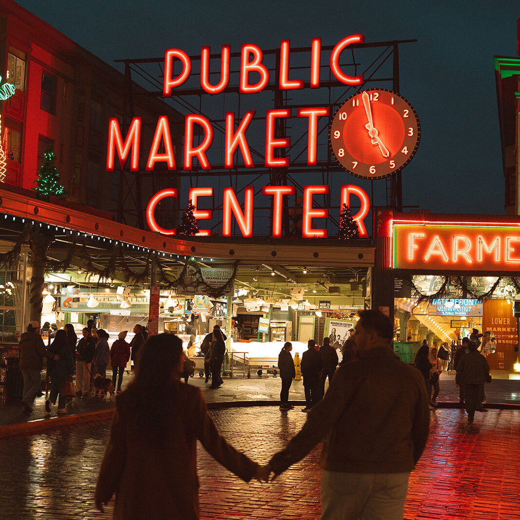 Cinematic couple walking under Public Market Center sign in Seattle for their engagement session