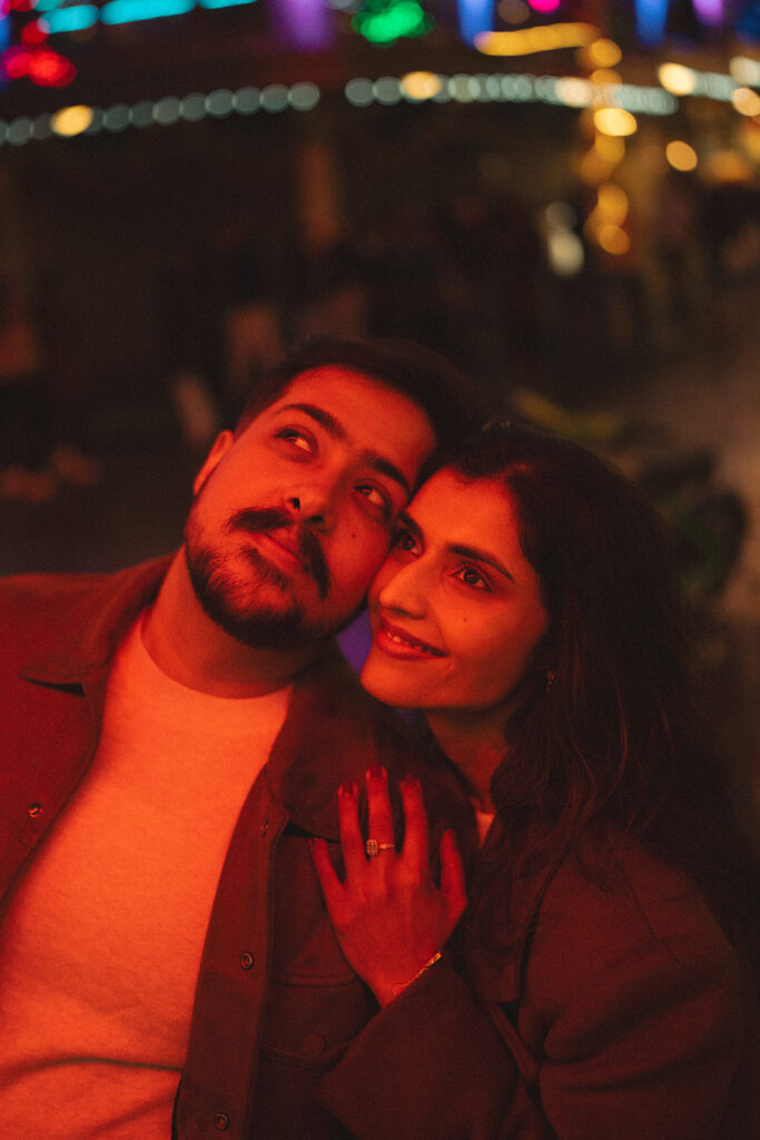 Cinematic couple getting cozy under the red glowing light of pike place market in Seattle