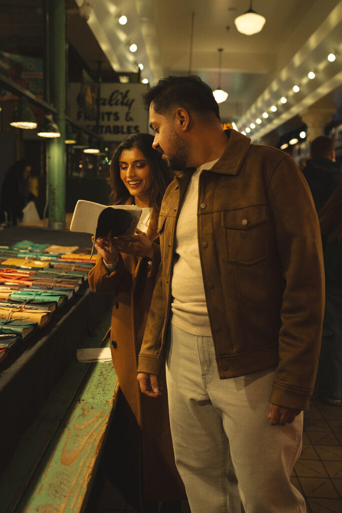 A cinematic couple looking through a book at Pike Place Market