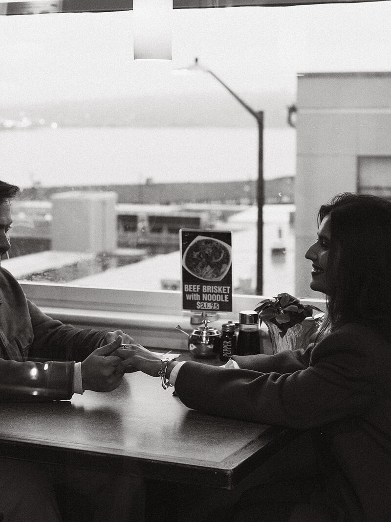Cinematic couple holding hands over a table as they sit at the diner