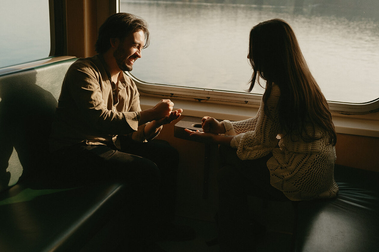 Couple playing rock paper scissors while sitting on a Washington State Ferry