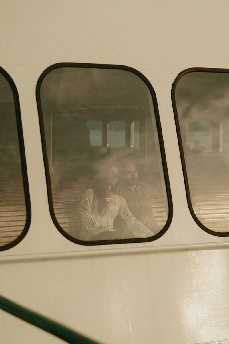 Couple sitting on the Washington State Ferry, looking out the window during golden hour